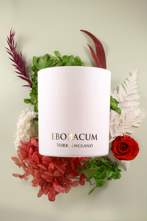 White candle with 'Eboracum York, England' text surrounded by flowers on a light background