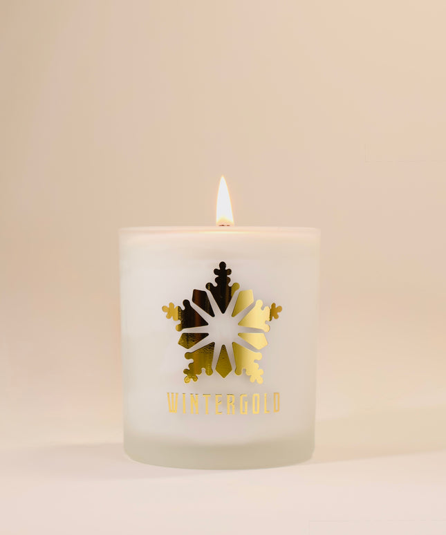 Candle with a gold snowflake design and 'Wintergold' text on a beige background